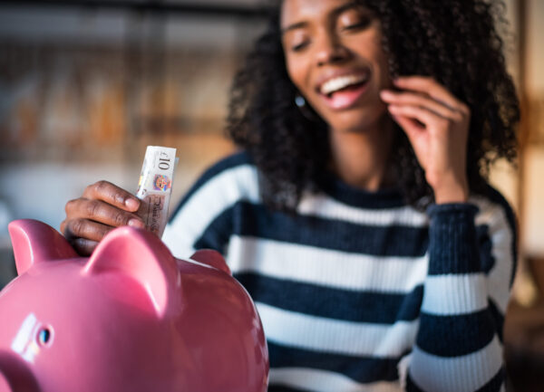 Black young woman with pink saving piggy bank