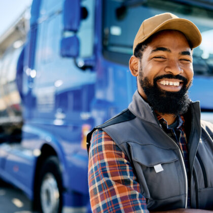 Happy African American truck driver on parking lot looking at camera. Copy space.